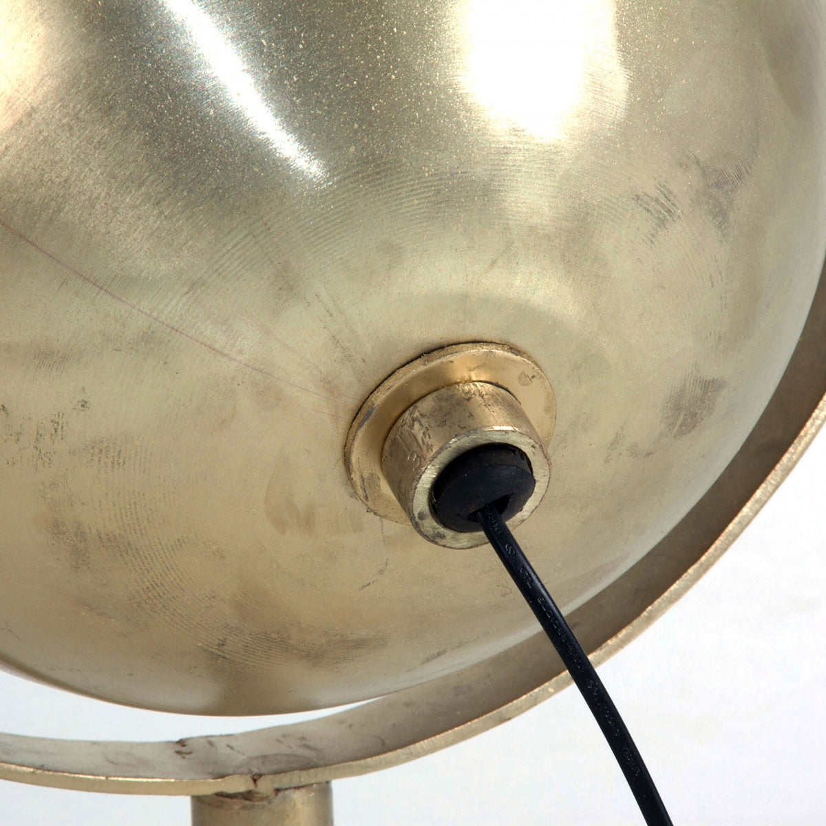 Primer plano de la parte trasera de la Lámpara de sobremesa en hierro y latón Barzy con acabado oro mate, mostrando un cable de alimentación negro enchufado a un enchufe circular en verdadero estilo Art Déco.