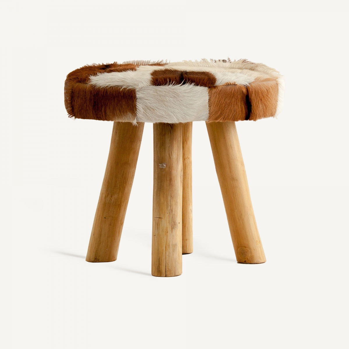 El Taburete bajo en madera de pino y piel Dallas cuenta con cuatro patas y un asiento redondo tapizado en piel de vaca marrón y blanca, ejemplificando la elegancia del diseño nórdico.