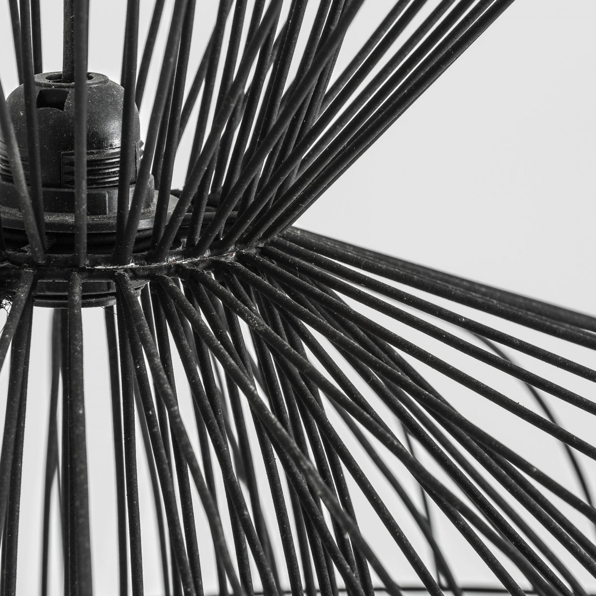 Primer plano de varillas de metal negro entrecruzadas que crean un patrón geométrico sobre un fondo liso, resaltando el diseño industrial elegante de la Lámpara colgante de hierro negro Sealza.