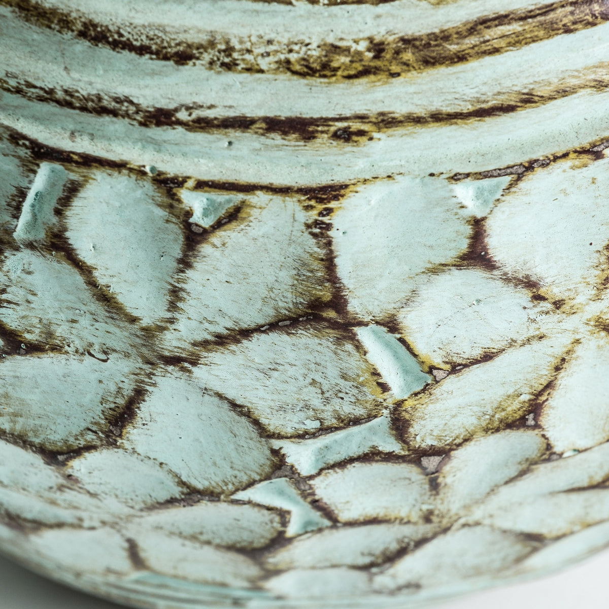 Primer plano de la Lámpara de mesa en terracota verde Loto, mostrando su superficie cerámica con un patrón texturizado en forma de hojas en tonos azul pálido y marrón.