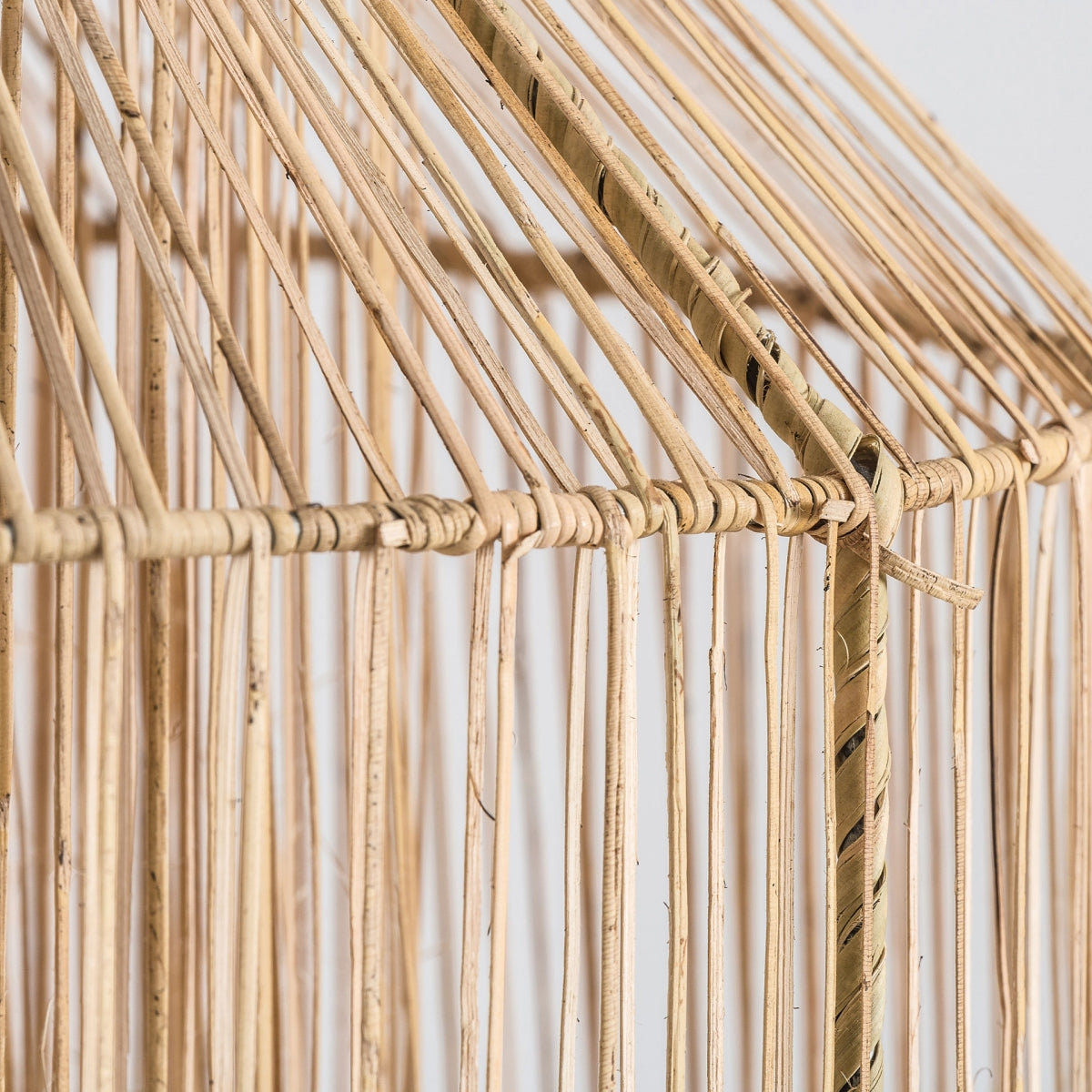 La Lámpara colgante en ratán marrón Olga presenta un primer plano de delgadas varas de bambú verticales atadas en un elegante patrón en forma de cuadrícula con conexiones diagonales en la parte superior, mostrando un diseño geométrico elegante.
