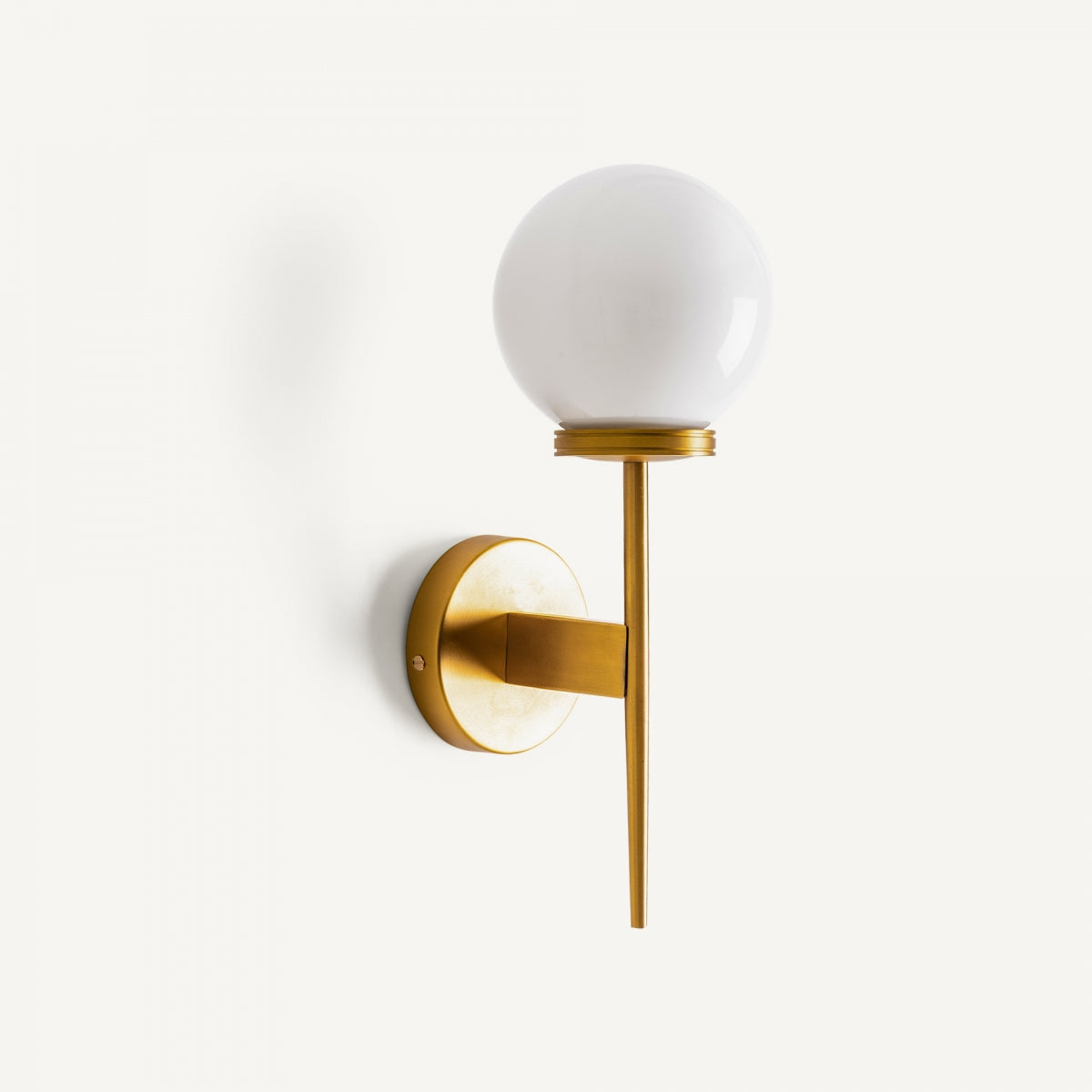 El aplique de pared en latón dorado y cristal opalino Bolar presenta una pantalla esférica de cristal opalino sobre una base cilíndrica de latón dorado, destacando su diseño moderno frente a un fondo blanco sencillo.