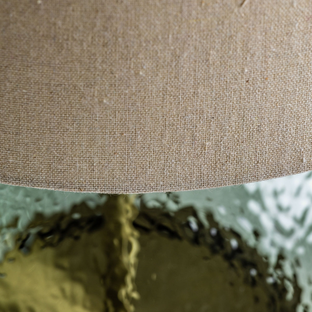 Primer plano de una pantalla de tela beige de la Lámpara de mesa en vidrio verde y metal Lasi, que presenta una base de vidrio verde texturizado y un elegante diseño realizado con materiales de alta calidad.
