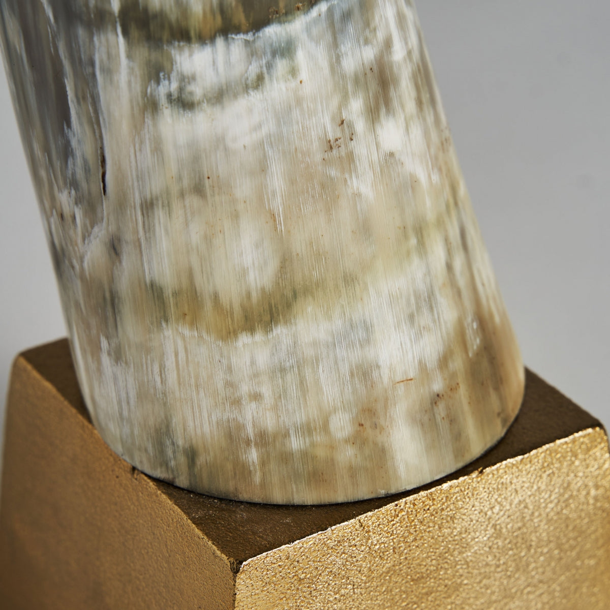 Primer plano de la Figura decorativa de resina negra y aluminio Zonza, que presenta una forma de resina negra suave y pulida sobre una base en tono dorado, perfecta para aportar exclusividad y sofisticación a cualquier ambiente de diseño nórdico.