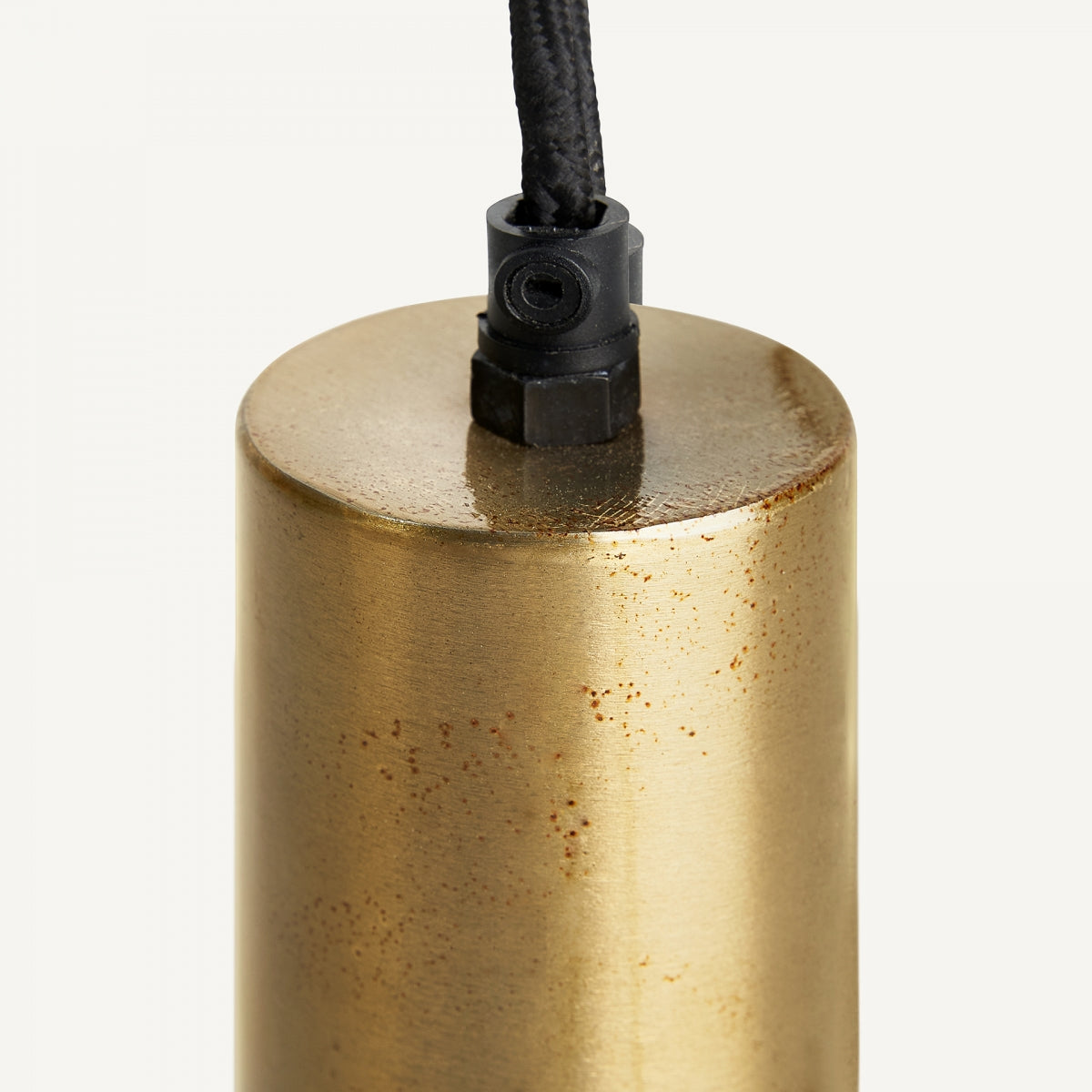 Primer plano de la Lámpara colgante en hierro negro y dorado Snok, mostrando su pantalla cilíndrica con acabado en latón con diseño art déco y un cordón negro unido en la parte superior.