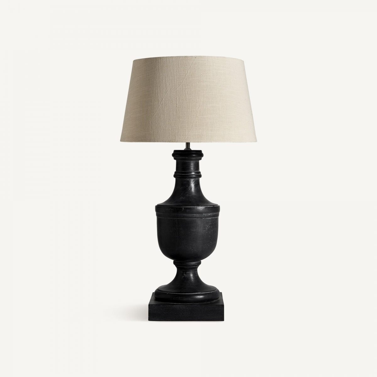 La lámpara de mesa en madera de mango Mexe presenta un acabado negro, pantalla de tela beige y base cuadrada para una iluminación acogedora, mostrada sobre un fondo blanco liso.