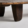 Primer plano de una pata de mesa Erara de mesa de centro rectangular en madera de teka que presenta un diseño triangular y rústico en madera de teca maciza, unida a un tablero de mesa texturizado con una artesanía exquisita sobre un fondo liso.