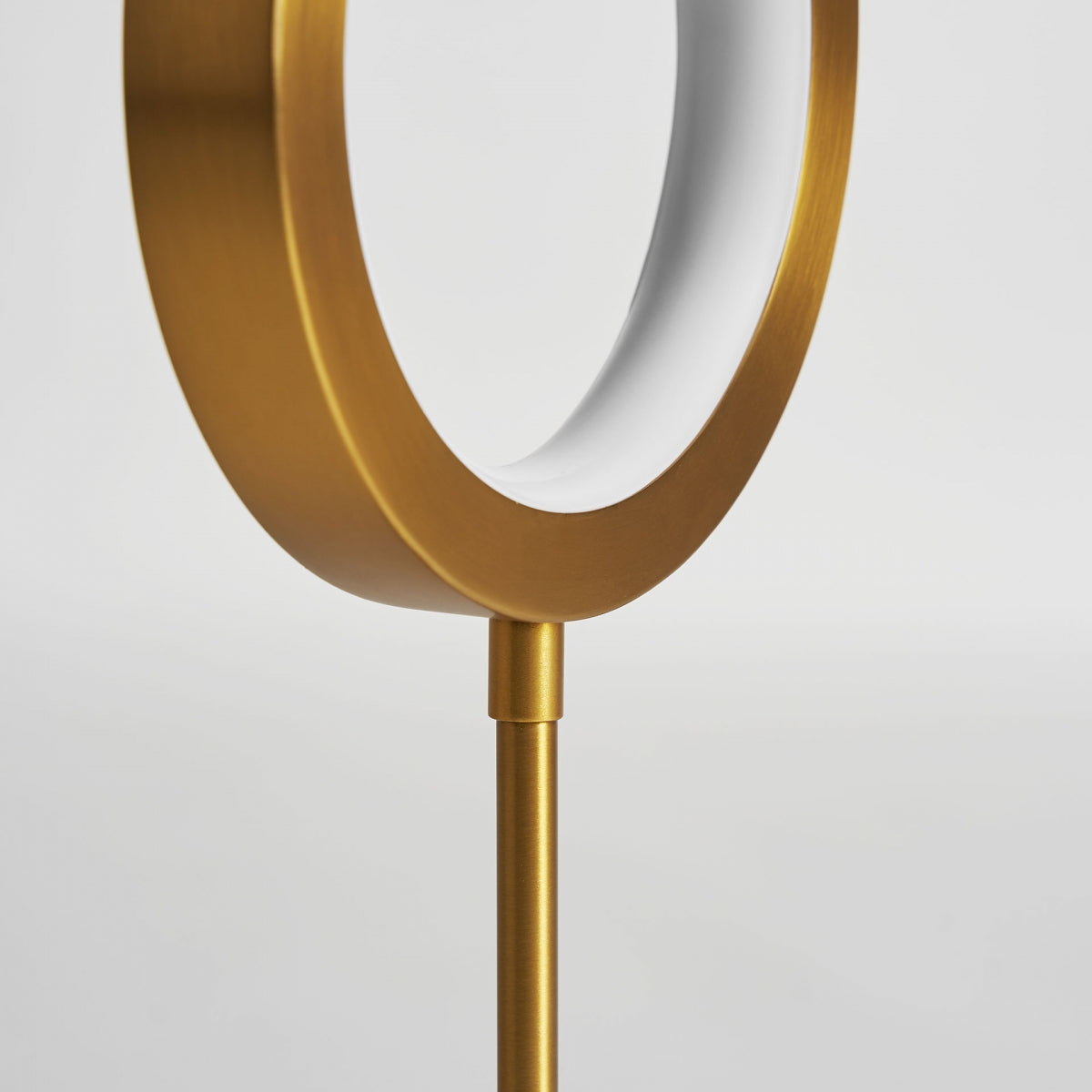 Primer plano de la Lámpara de mesa en latón dorado MC 20, una moderna lámpara de mesa circular dorada y blanca con un diseño minimalista inspirado en el art déco, fotografiada sobre un fondo blanco liso.