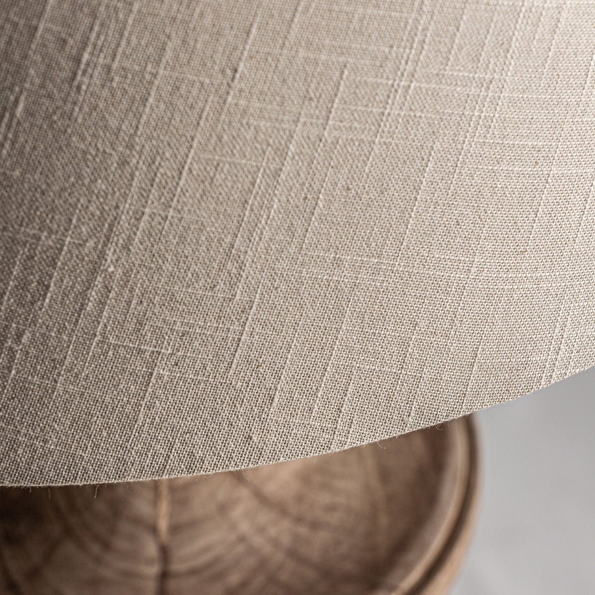Primer plano de la pantalla beige texturizada y la base de madera de mango de la Lámpara de mesa en madera de mango Bolsa, que ofrece un encanto provenzal.