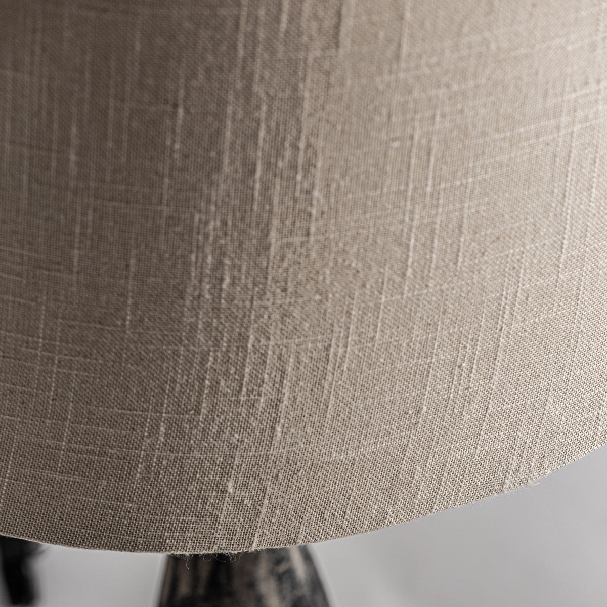 Primer plano de la lámpara de mesa Larza en madera de mango, con pantalla de tela beige con un sutil patrón de tejido texturizado, elaborada con diseño artesanal y materiales de primera calidad bajo una iluminación suave.
