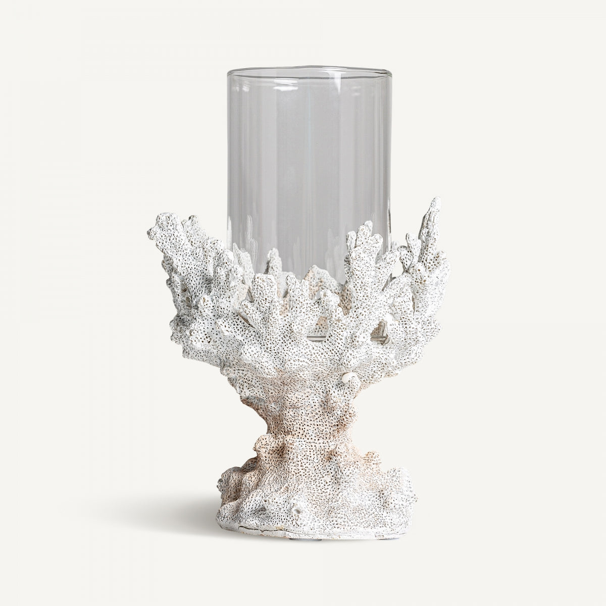 El Portavela en resina y cristal Arrecife S presenta un cuerpo de vidrio cilíndrico transparente elegantemente sostenido por una base en forma de coral blanco en elegante resina blanca, personificando el diseño moderno sobre un fondo liso.