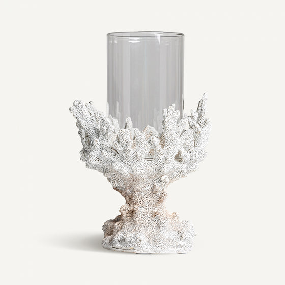 El Portavela en resina y cristal Arrecife S presenta un cuerpo de vidrio cilíndrico transparente elegantemente sostenido por una base en forma de coral blanco en elegante resina blanca, personificando el diseño moderno sobre un fondo liso.