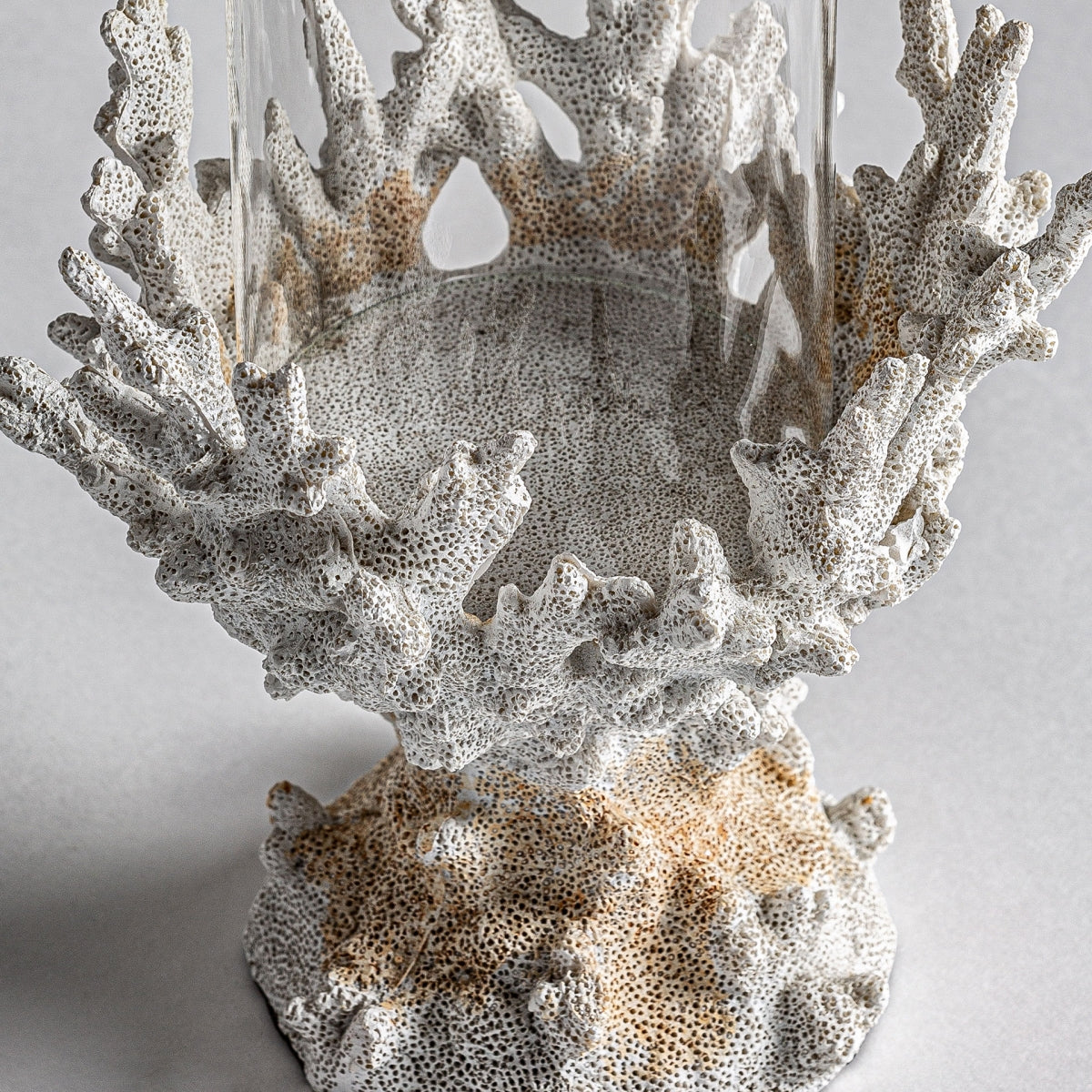 Portavelas decorativo nórdico en resina Arrecife M con intrincados patrones inspirados en el coral en beige y blanco, que sostiene un jarrón cilíndrico de vidrio transparente sobre un fondo gris claro, ideal para realzar la decoración moderna.