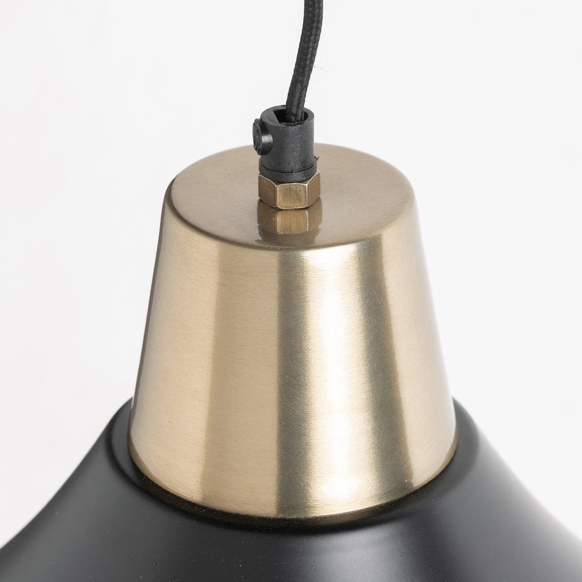 Detalle de la Lámpara colgante en hierro oro-negro Noi con casquillo de metal cepillado, cordón negro y parte de su pantalla cónica negra mate, destacando una elegante iluminación sobre un fondo blanco.