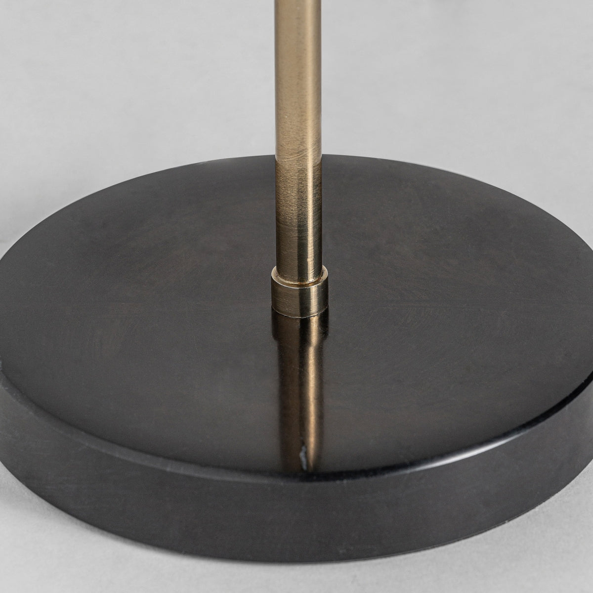 Primer plano de la base redonda de mármol negro de la lámpara de mesa Erte con una barra de hierro vertical en el centro, mostrando su elegante diseño art decó.