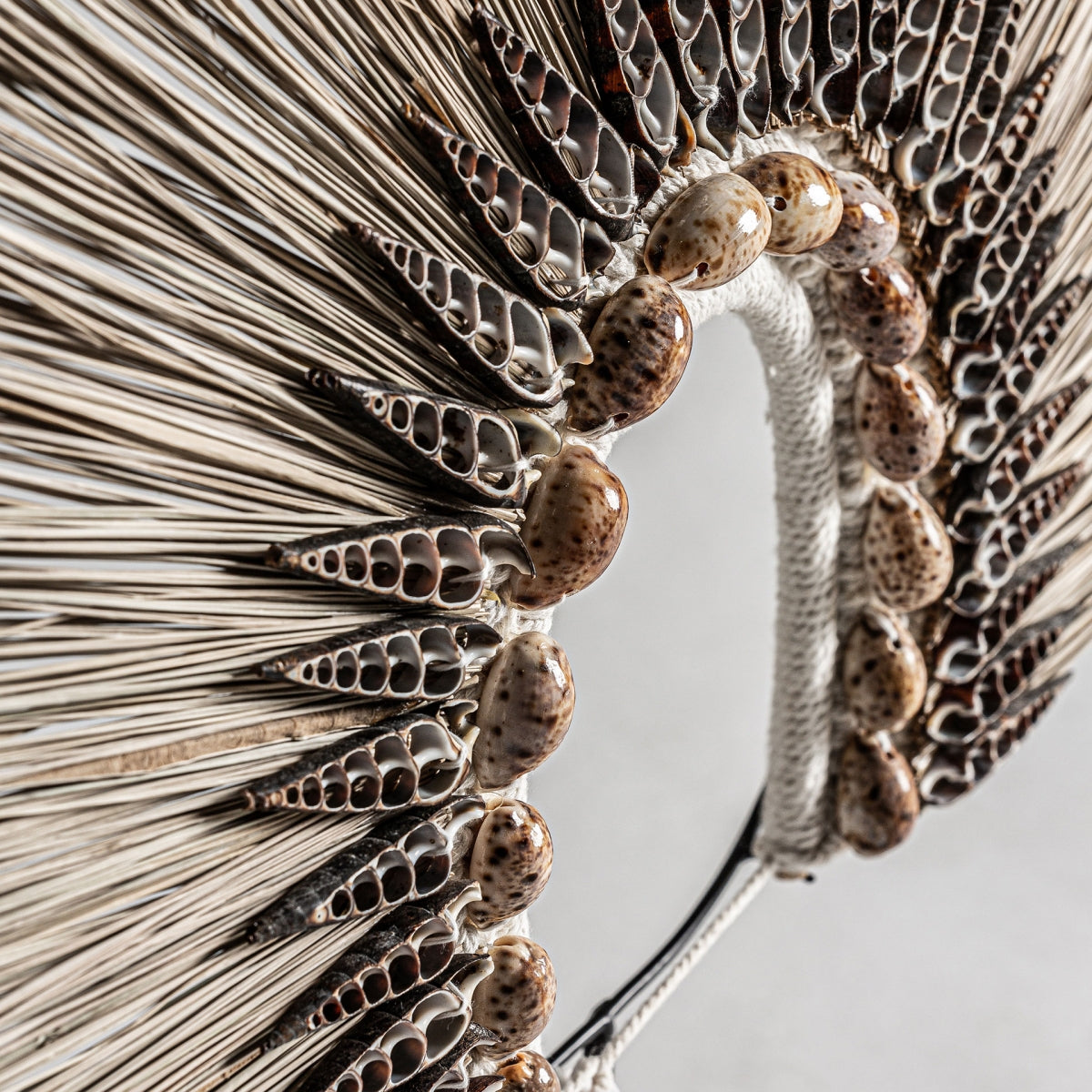 Primer plano de la Figura decorativa en fibra natural y concha Etna, que muestra filas de conchas marinas marrones y blancas en un diseño circular sobre fibra natural tejida, perfecta para agregar una decoración original a cualquier espacio.