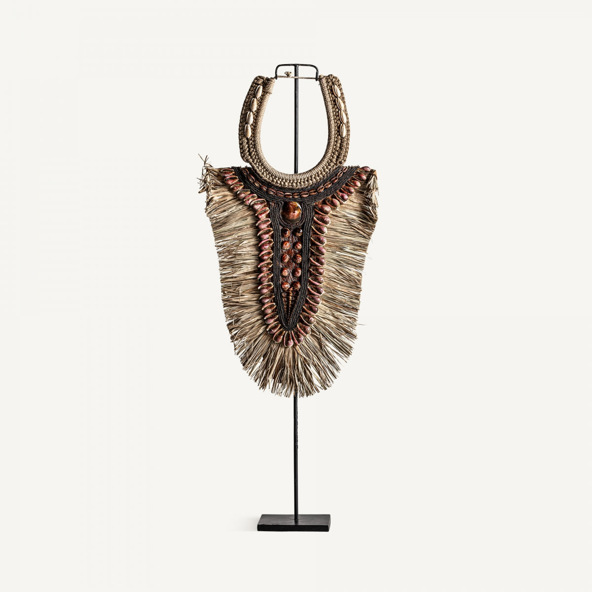 La figura decorativa en fibra natural estilo étnico Zarue, hecha de fibras naturales, conchas y cuentas, se exhibe sobre soporte metálico y es ideal para aportar un toque étnico a la decoración de interiores.