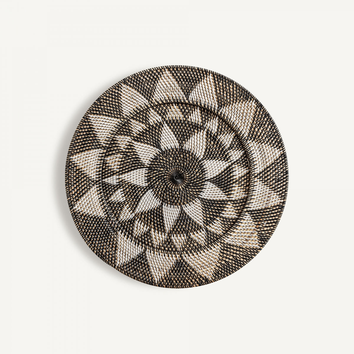 Panel decorativo de ratán étnico Zirba: tapa tejida en patrón geométrico blanco y negro con diseño radial, ideal para destacar en cualquier pared blanca.
