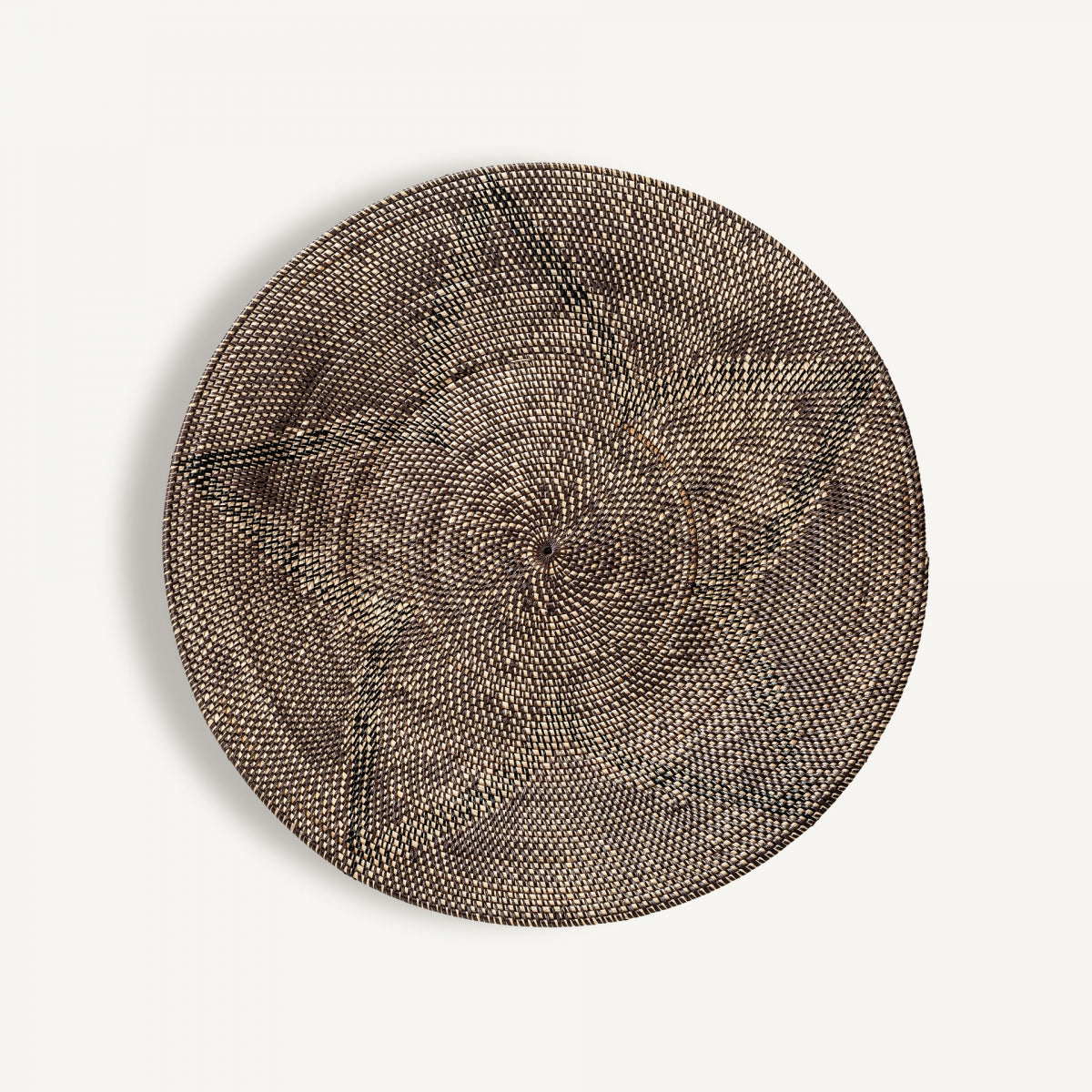 El Panel decorativo de ratán S.Zirba es un cesto redondo y plano, tejido con ratán de alta calidad, con diseño étnico simétrico en tonos marrón y beige, fotografiado sobre fondo blanco.