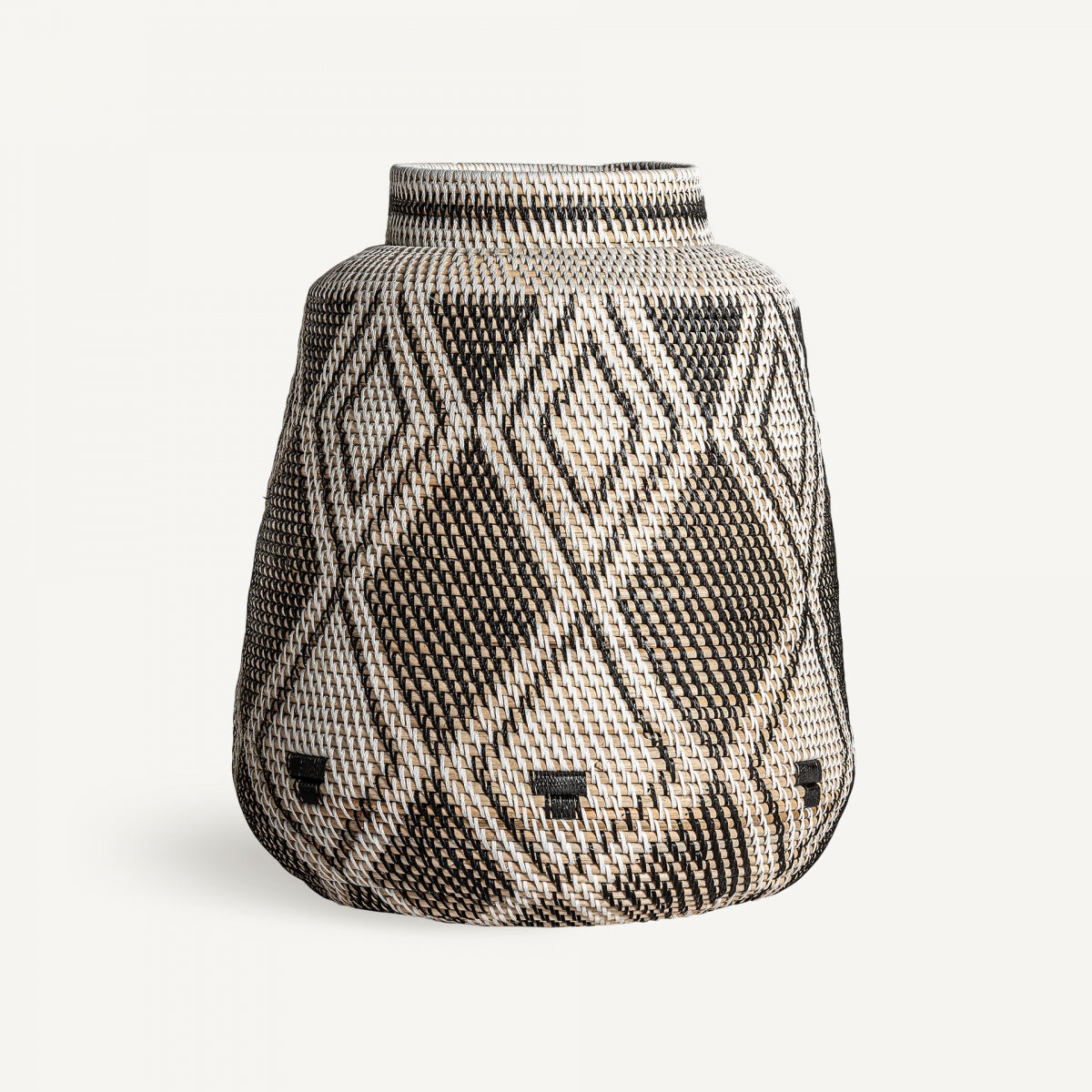 El Jarrón en ratán étnico Zirba presenta base ancha, boca estrecha y patrones geométricos en blanco y negro, ideal para decoración étnica o como pieza llamativa en cualquier sala.