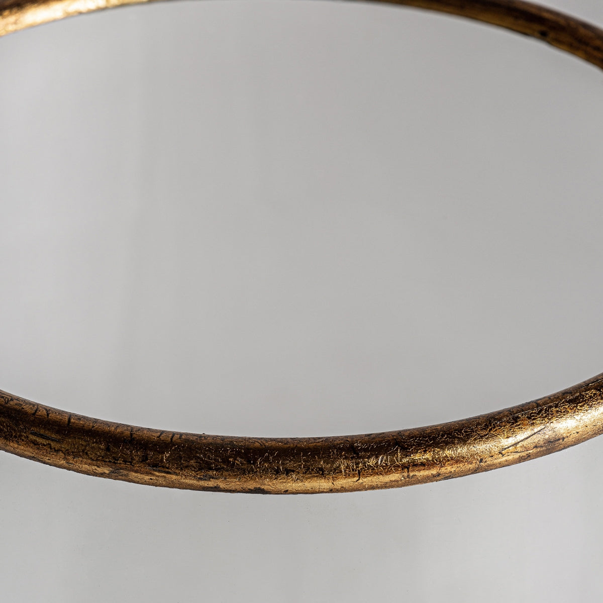 Primer plano de una mesa circular de vidrio con un borde de bronce metálico texturizado, que muestra el diseño vintage del Portavelas en madera y hierro mango que recuerda a un acabado en oro envejecido.