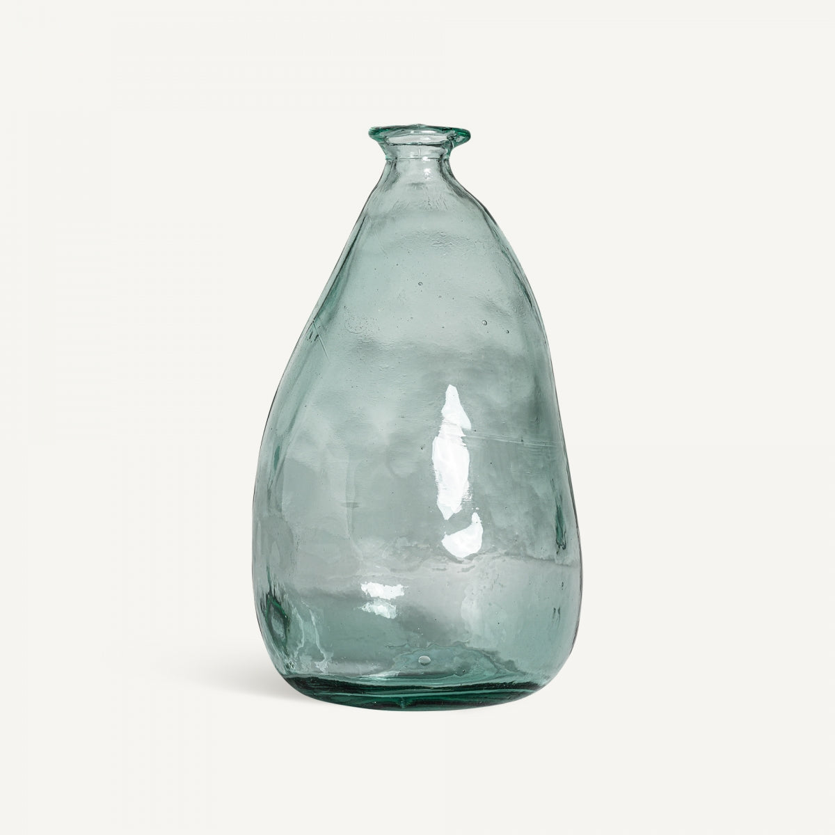 Un jarrón de vidrio reciclado Sumaya W transparente, ligeramente deforme, con un cuello estrecho y una base ancha se muestra sobre un fondo blanco liso, agregando un toque de diseño sostenible.
