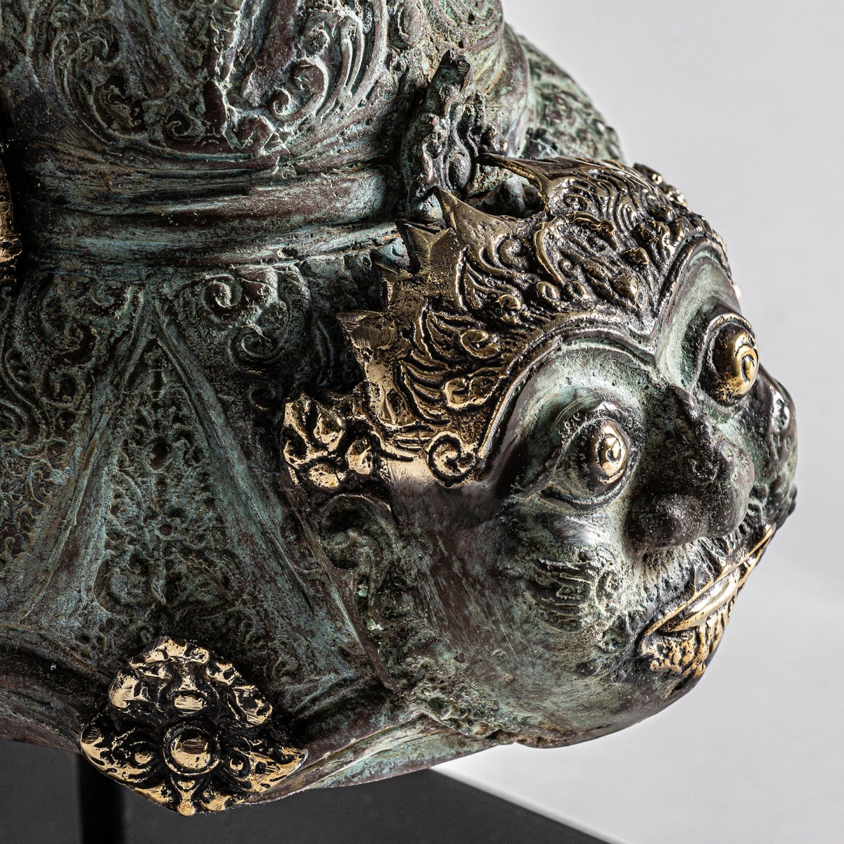 Primer plano de la Figura decorativa oriental en bronce Yasmin, que muestra un rostro ornamentado y expresivo con intrincados detalles dorados y una superficie texturizada con acabado envejecido.