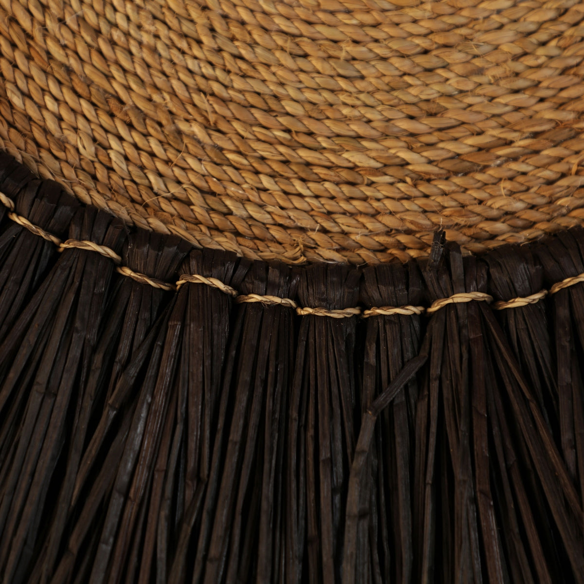 Primer plano del panel decorativo en rafia boho Aura, que presenta un diseño de paja tejida y un borde de fibra oscura atado con un cordón claro, ideal para brindar encanto boho a cualquier espacio.