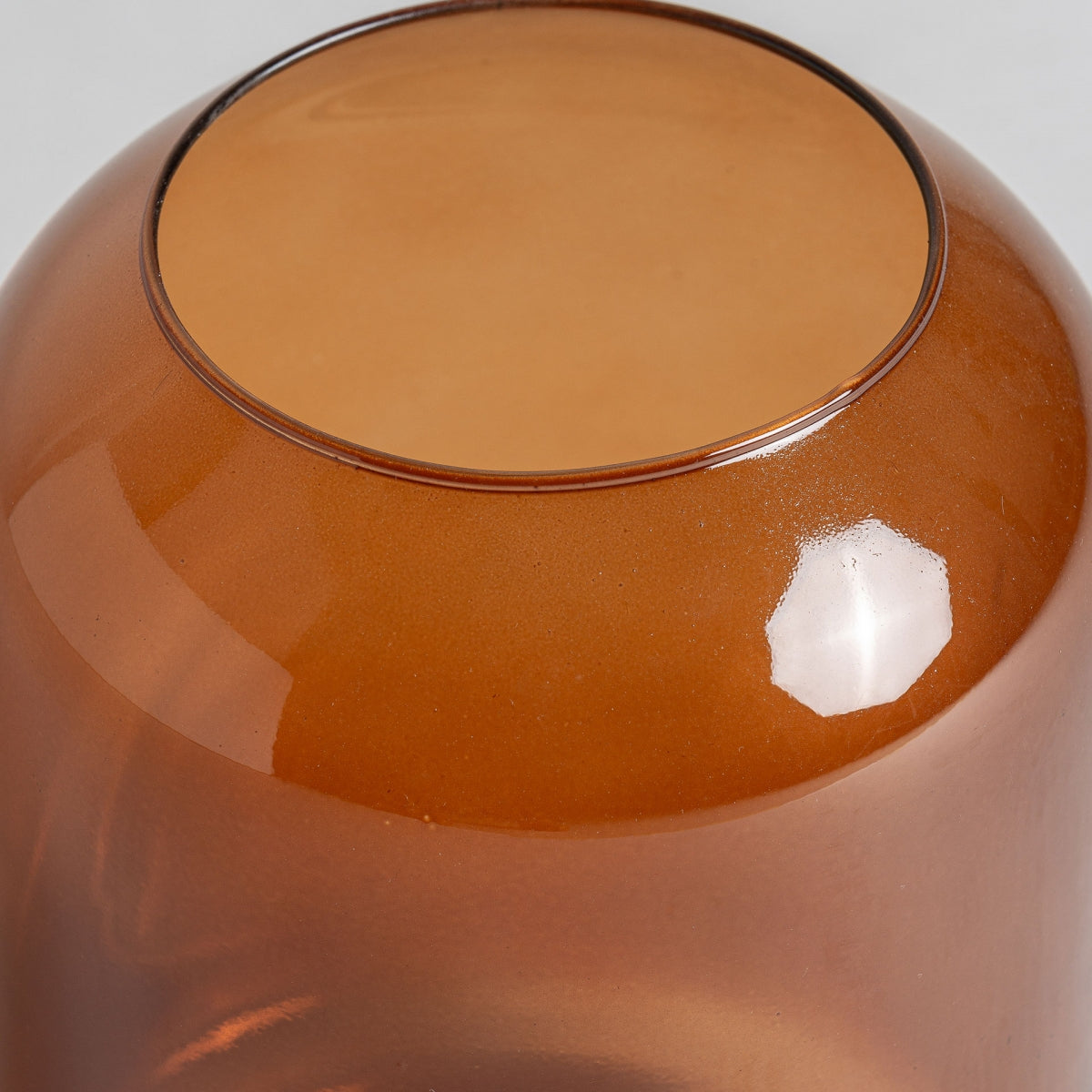 Primer plano del fondo de un Jarrón de vidrio ámbar Covasna Amb invertido, con una superficie lisa y reflectante, ideal para una decoración elegante.
