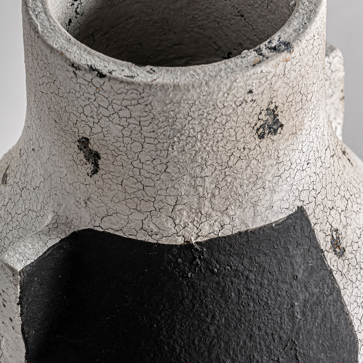 Primer plano del jarrón en terracota contemporáneo Mintlaw S, resaltando su superficie rugosa y agrietada en blanco con acentos negros irregulares, ideal para interiores modernos y minimalistas.