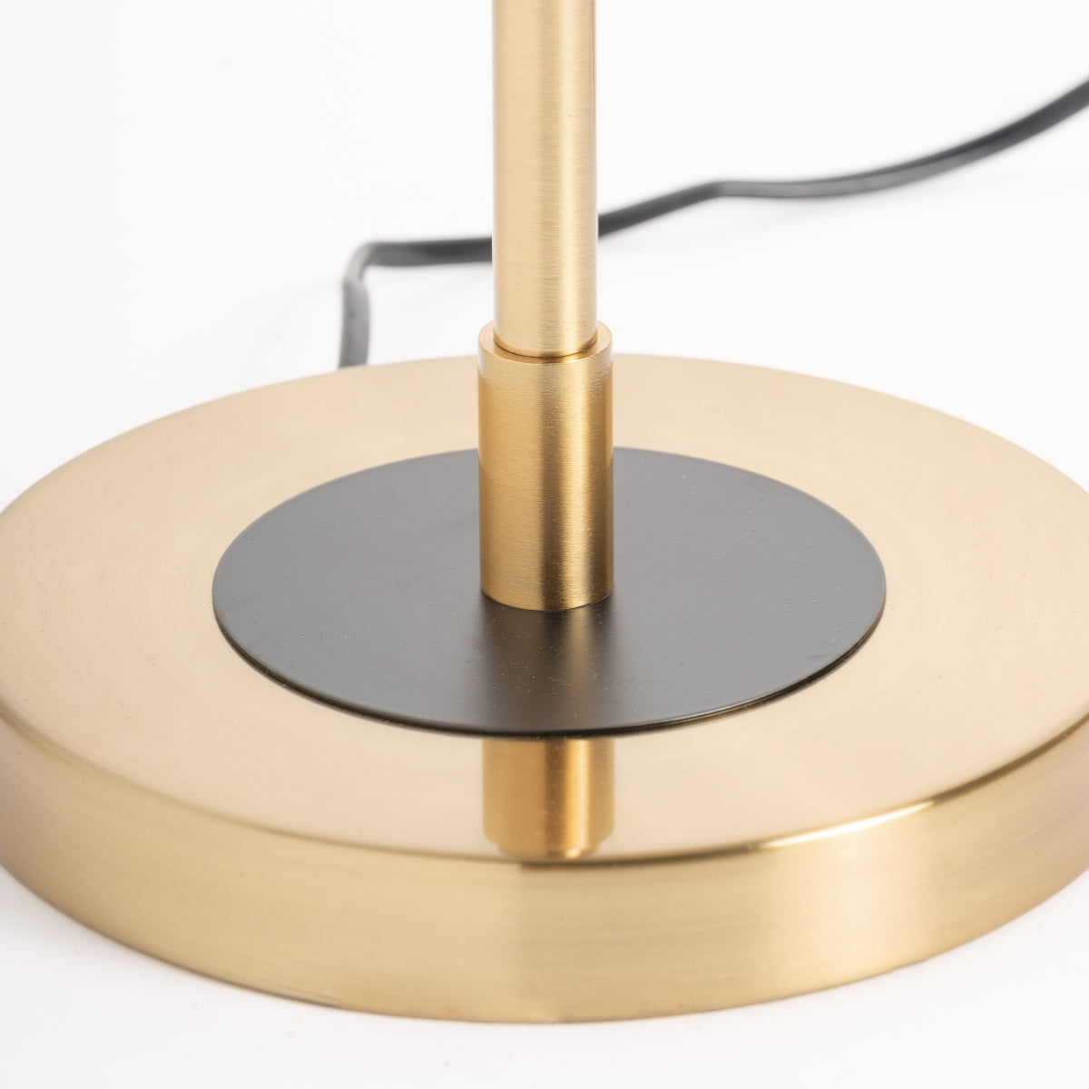 Primer plano de la lámpara de sobremesa de hierro y acrílico MAOZ con base de oro cepillado, detalle circular negro y cable de alimentación negro, perfecta para agregar lujo sutil y estilo art déco a cualquier espacio.