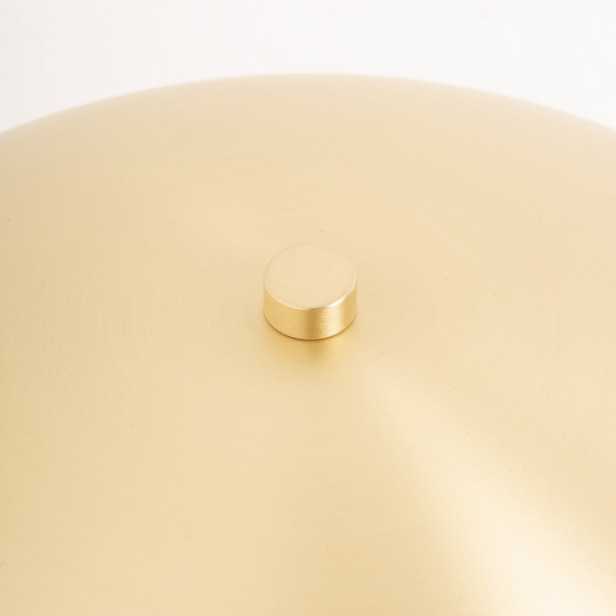 Primer plano de la Lámpara de mesa en hierro dorado Lena mostrando su cúpula de latón mate con un pomo redondo central, presentando un elegante estilo art déco y acabado dorado característico de esta lámpara de mesa.