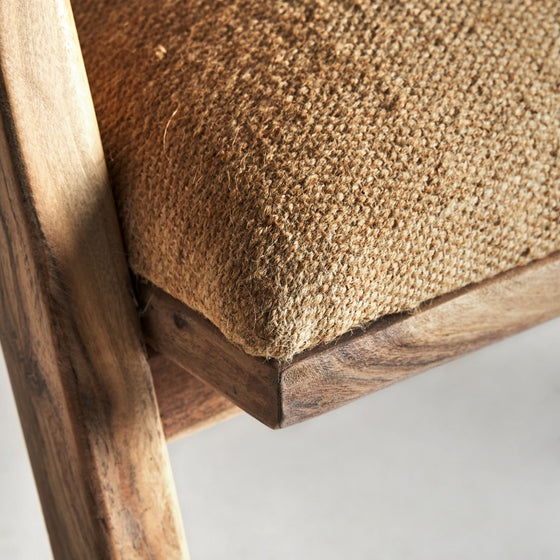Primer plano de un Sillón de madera y yute Elgin, destacando su estructura de madera y su cojín tejido en color beige que realzan su diseño vintage.