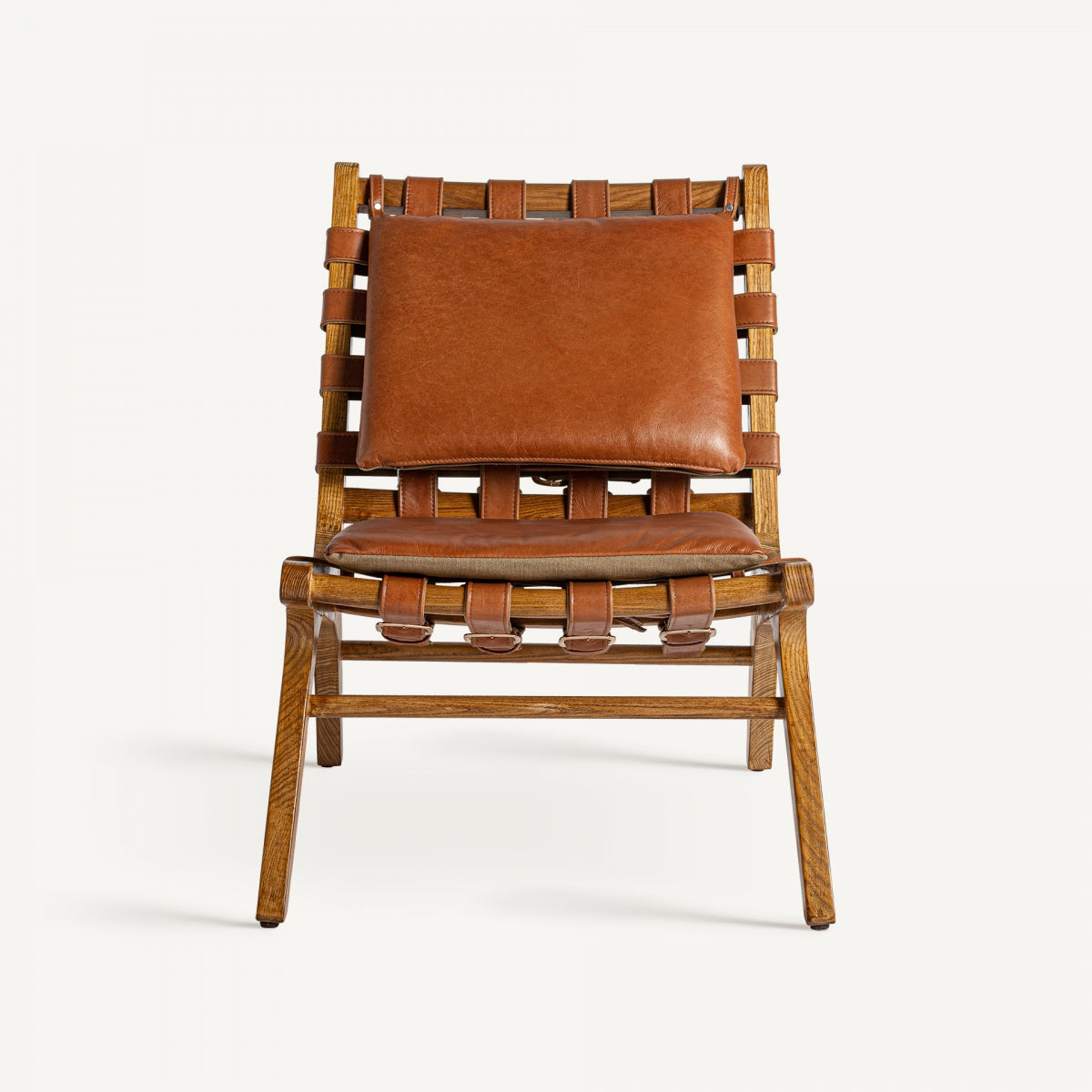 El sillón en piel y madera de fresno Alford presenta un respaldo y un asiento con correas de cuero tejido combinados con un cojín de cuero marrón sobre un marco de madera clara, evocando un estilo art déco.