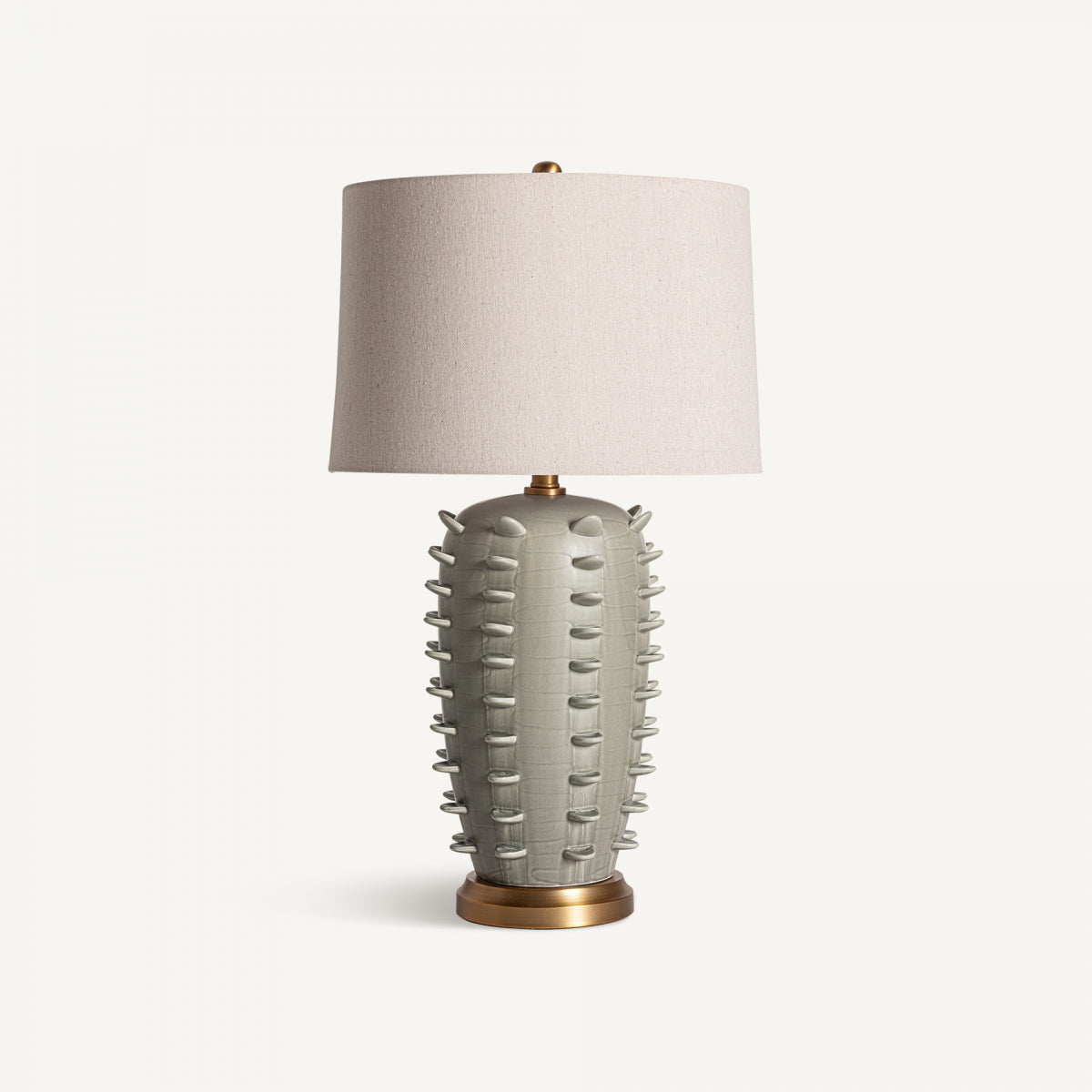 Lámpara de mesa en cerámica verde Marais con base texturizada inspirada en cactus, fondo circular dorado y pantalla beige, perfecta para aportar luz cálida y estilo Art Deco a cualquier ambiente.