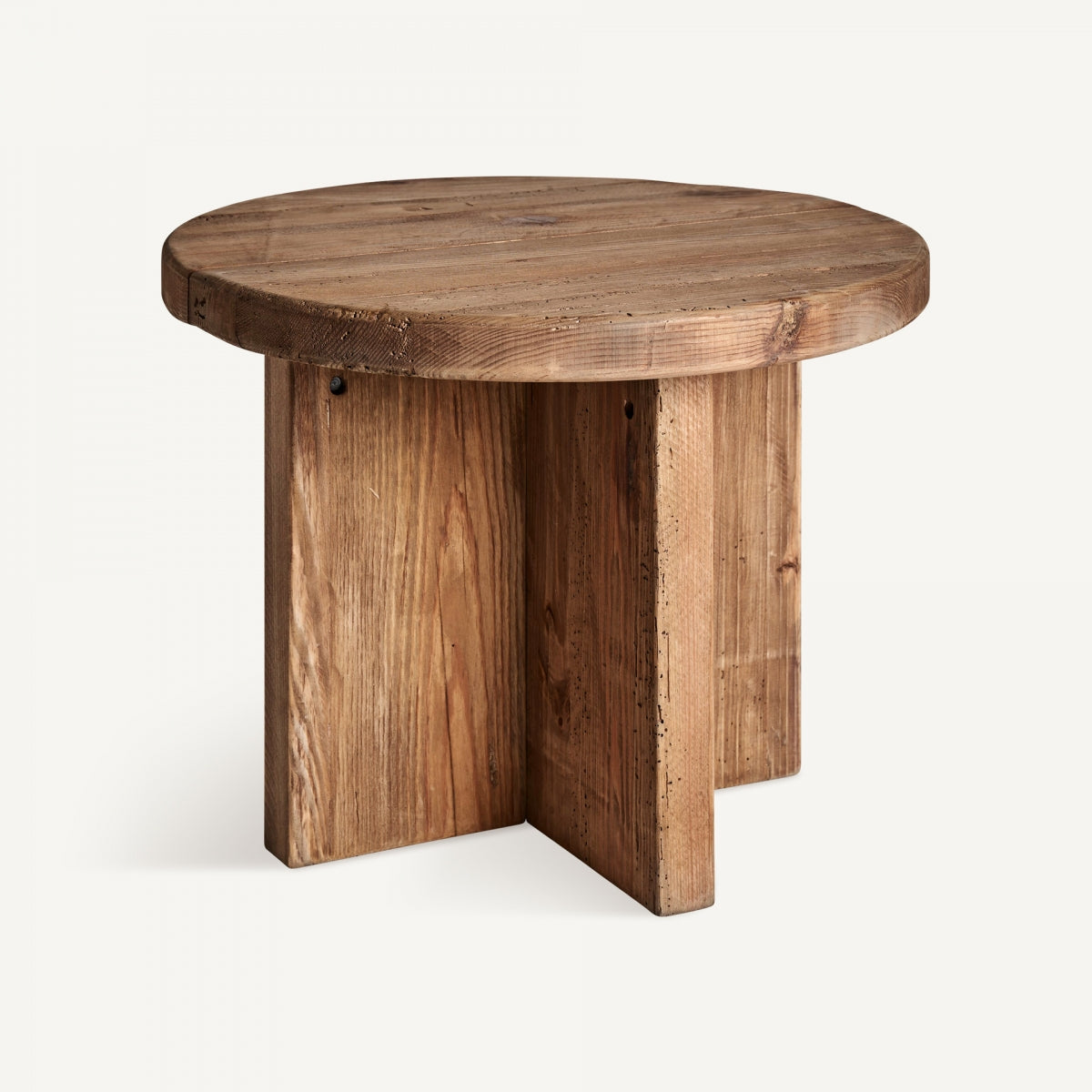 La mesa auxiliar en madera de pino reciclado Crissey presenta un diseño redondo de madera con un acabado rústico y una base en forma de cruz, combinando a la perfección materiales ecológicos con una elegancia atemporal.