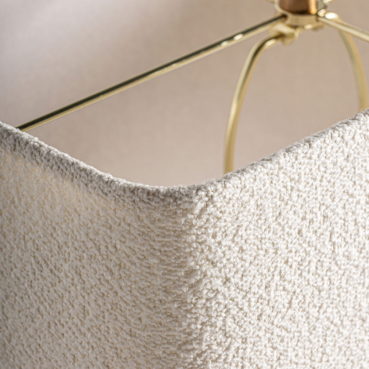 Primer plano de la pantalla cuadrada de color blanco texturizado con marco y remate de metal dorado, destacando el diseño exclusivo de la Lámpara de mesa en travertino y hierro Orion.
