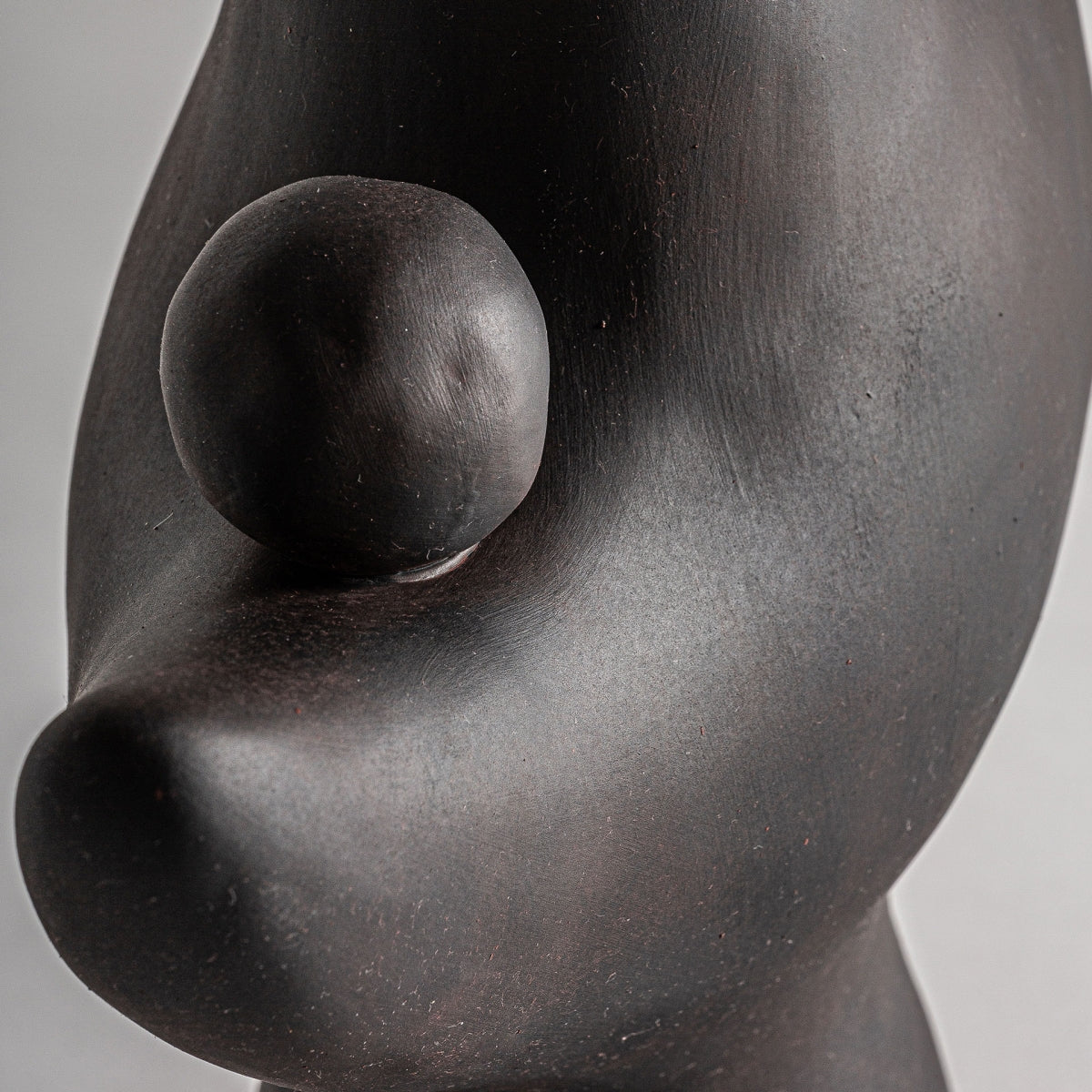 La figura decorativa en cerámica negra Nohae es una escultura abstracta y suave con curvas orgánicas y un pequeño elemento esférico, que exuda un encanto art déco que cautiva la mirada.