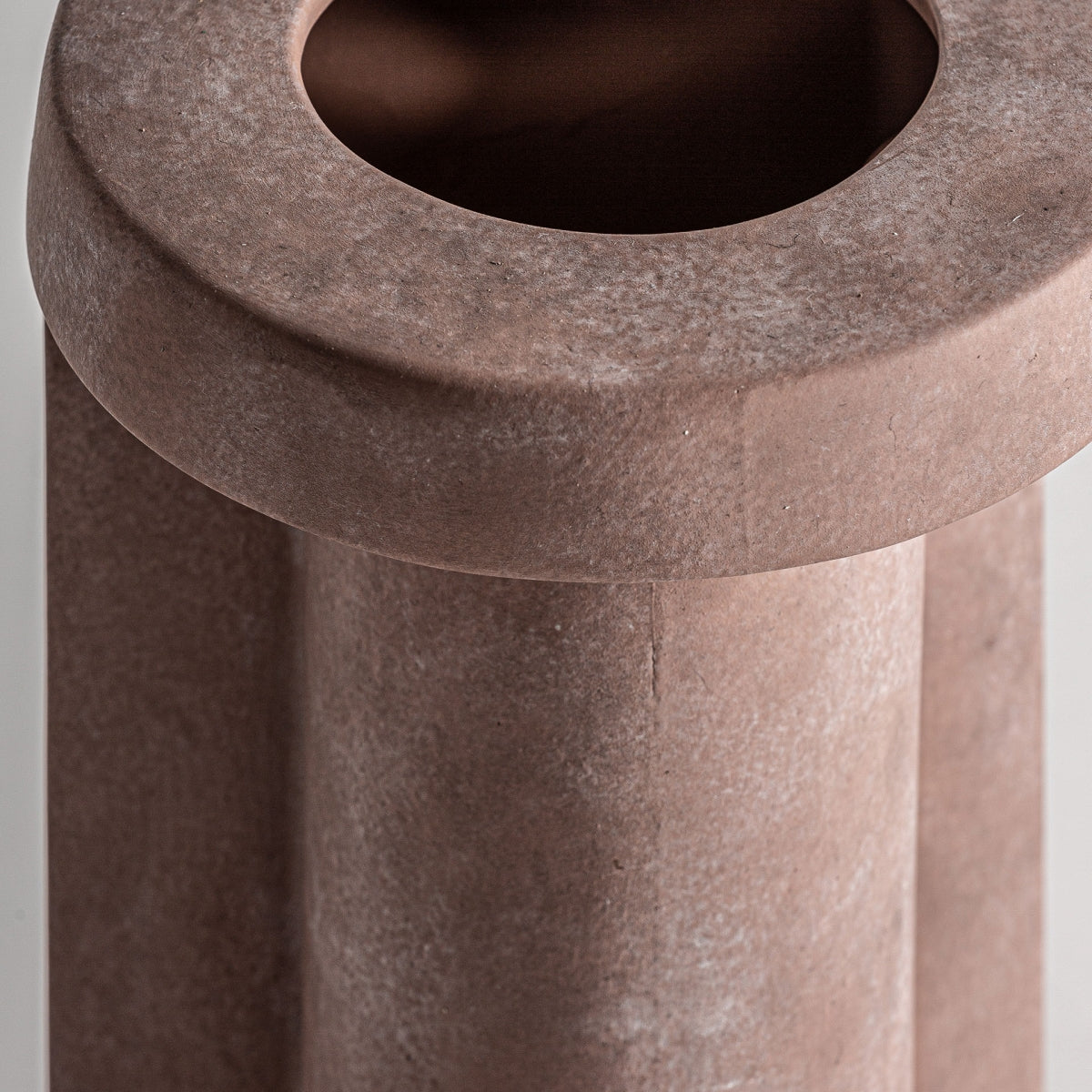 Una vista detallada de un diseño redondo y texturizado en marrón evoca la elegancia de la cerámica art déco con su centro hueco y superficie lisa. Ideal para la decoración moderna, se asemeja mucho al jarrón de cerámica decorativa Leif.