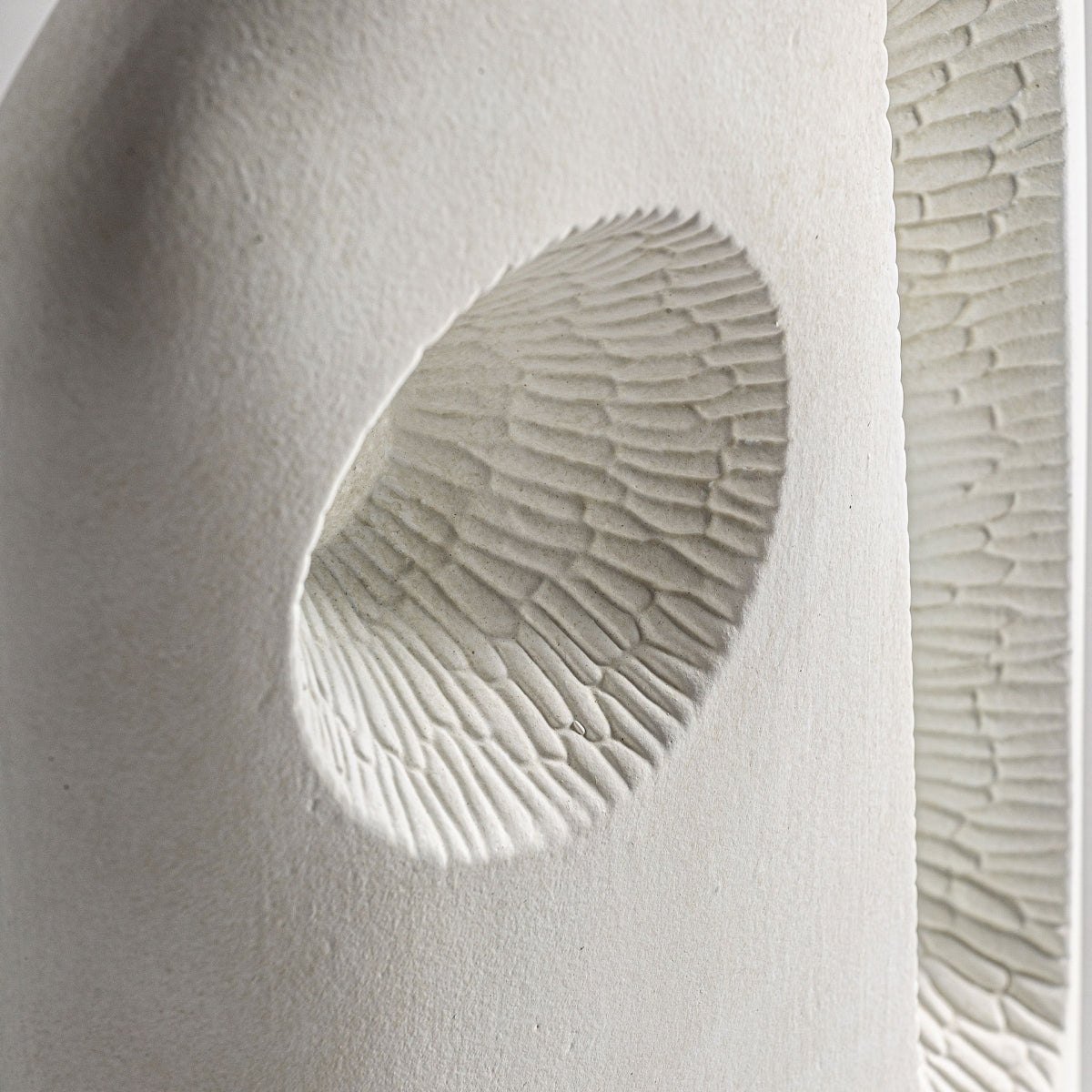 Primer plano del Jarrón contemporáneo de cerámica blanca Leghe en estilo Art Déco, que muestra hendiduras circulares y texturas estriadas para un efecto de capas.