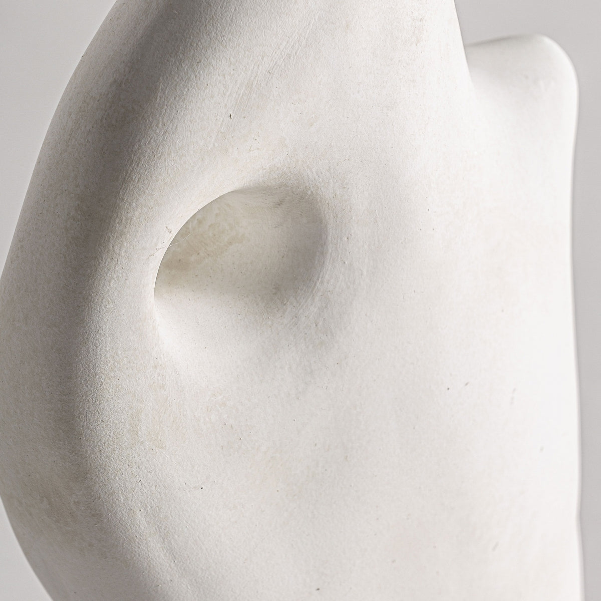 El Jarrón abstracto en cerámica blanca Leghe presenta un primer plano que se asemeja a parte de un rostro, con énfasis en una oreja y contornos sutiles, exudando elegancia de diseño art decó sobre un fondo neutro.