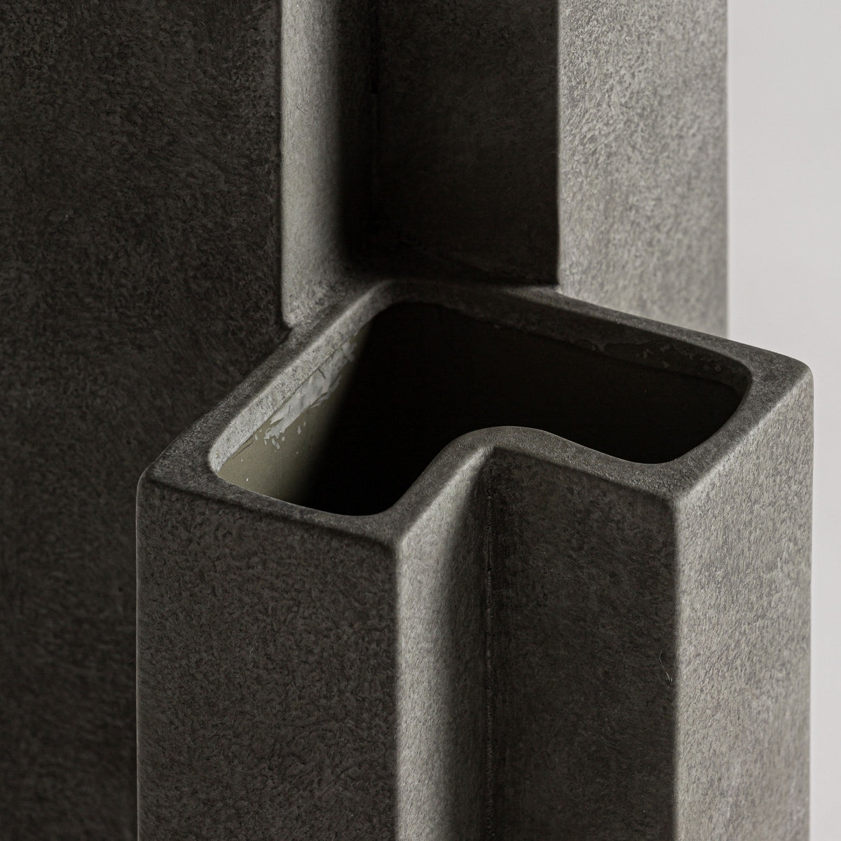 Primer plano del Jarrón estilo art deco en cerámica gris Kedha S, que presenta formas rectangulares que se cruzan y una sección hueca abierta inspirada en el estilo art deco.