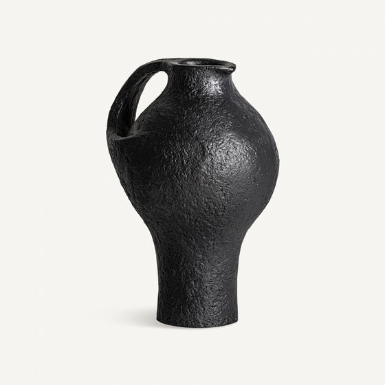 El Jarrón de resina negra Riley S es un jarrón de cerámica negra texturizada con una sola asa, cuerpo bulboso y cuello estrecho, perfecto para la decoración de interiores. Destaca elegantemente sobre un fondo blanco liso.