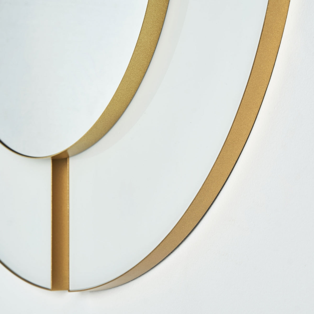 Primer plano del Espejo circular en cristal y hierro Bahiale (100x100 cm), un moderno espejo de pared art déco con marco de metal dorado, formas geométricas y líneas limpias: una elegante pieza de decoración de interior sobre un fondo blanco.