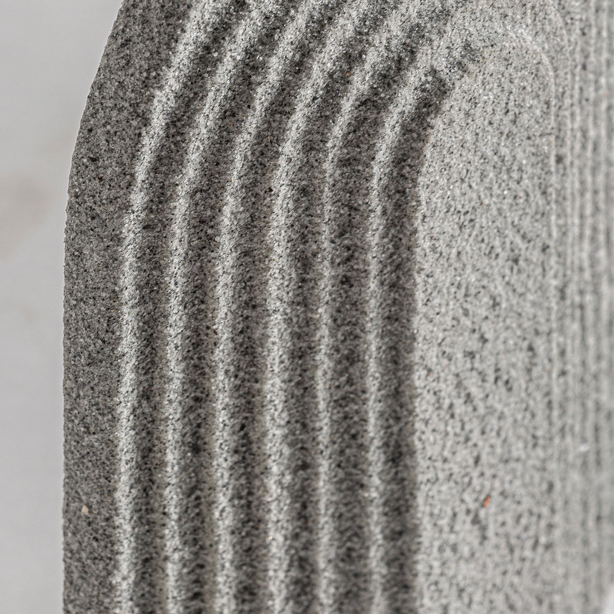 Primer plano de la superficie gris texturizada de la Figura decorativa de resina rugosa Tirso, con ranuras curvas espaciadas uniformemente, ideal para quienes buscan elegancia y estilo en sus espacios. Perfecto para proyectos de alta calidad.