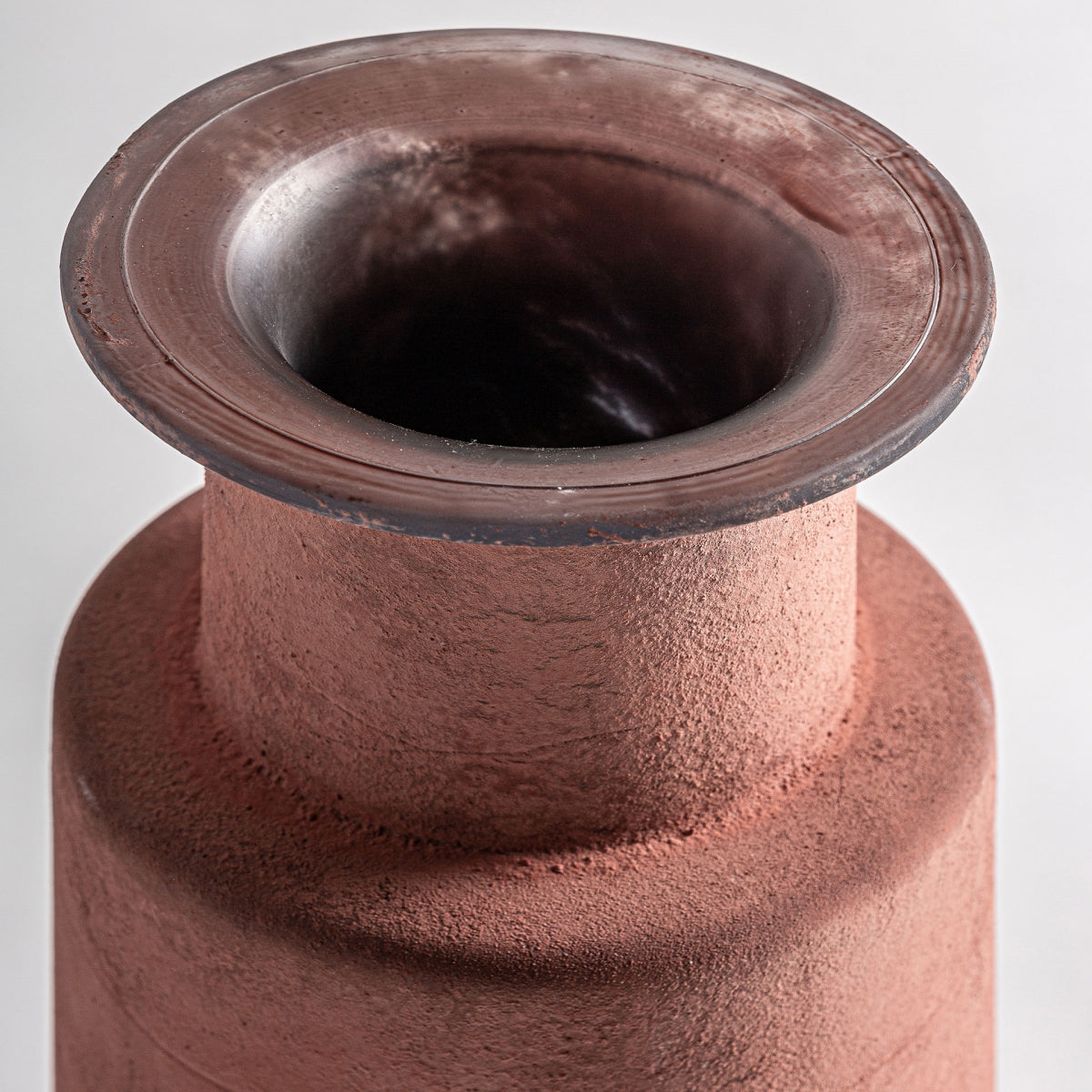 Un primer plano de la apertura del Jarrón de vidrio vintage Den, que presenta un acabado texturizado de color marrón rojizo sobre un fondo liso.