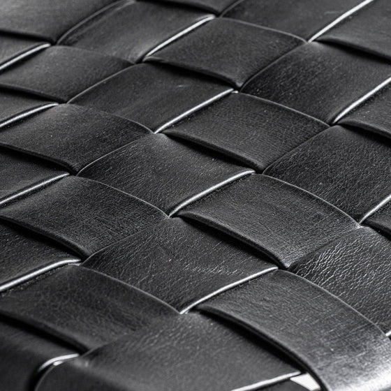 Primer plano de textura de cuero tejido negro con patrón tipo canasta, que recuerda al diseño contemporáneo de la Silla de comedor en hierro y piel Franey.