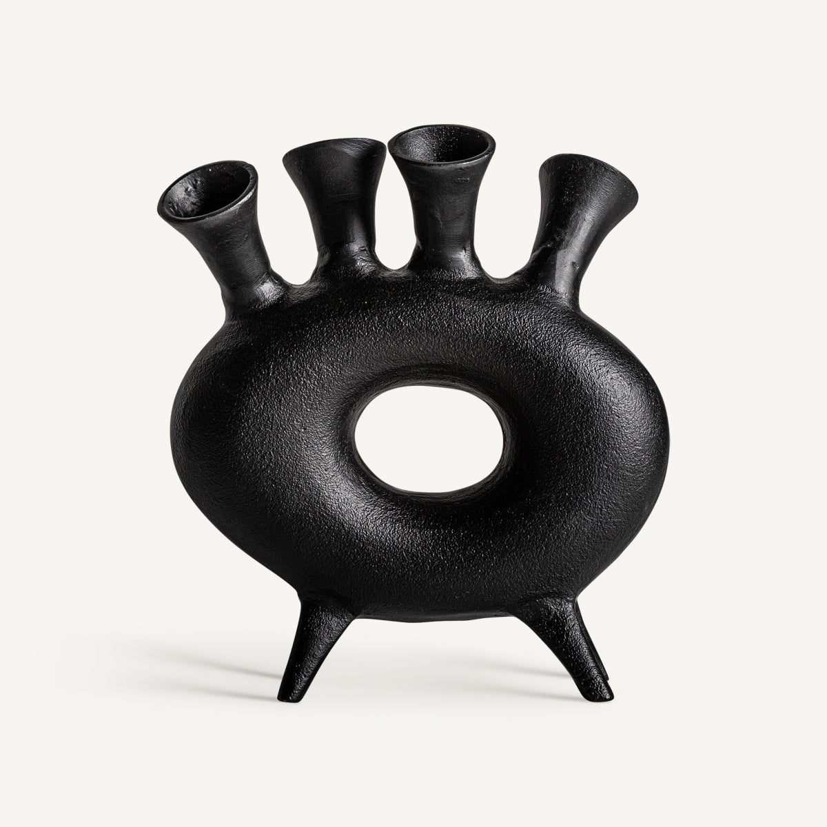 Figura decorativa en aluminio negro Davet con cuerpo redondo, orificio central, cuatro tubos en la parte superior y dos patas cortas; una pieza de arte contemporáneo sobre fondo blanco.