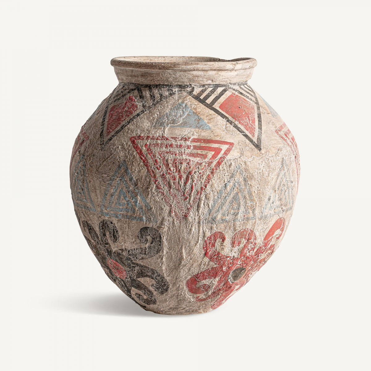 El jarrón en terracota multicolor Didac es un recipiente de cerámica de grandes dimensiones, de forma redonda y borde estrecho, que presenta dibujos geométricos y motivos florales en rojo, negro y azul sobre un fondo claro.