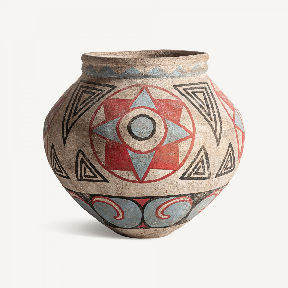 El Jarrón en terracota multicolor Heneo presenta patrones geométricos rojos, azules y negros, como círculos concéntricos, triángulos y estrellas estilizadas sobre su superficie redondeada.